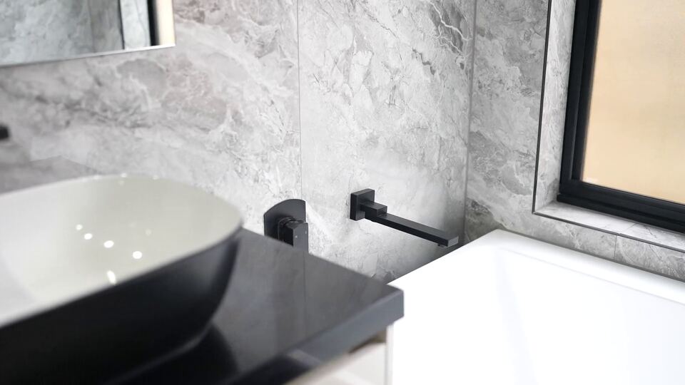Vanity with a black and white vessel basin, black tapware and grey marble-look tiles beside a window