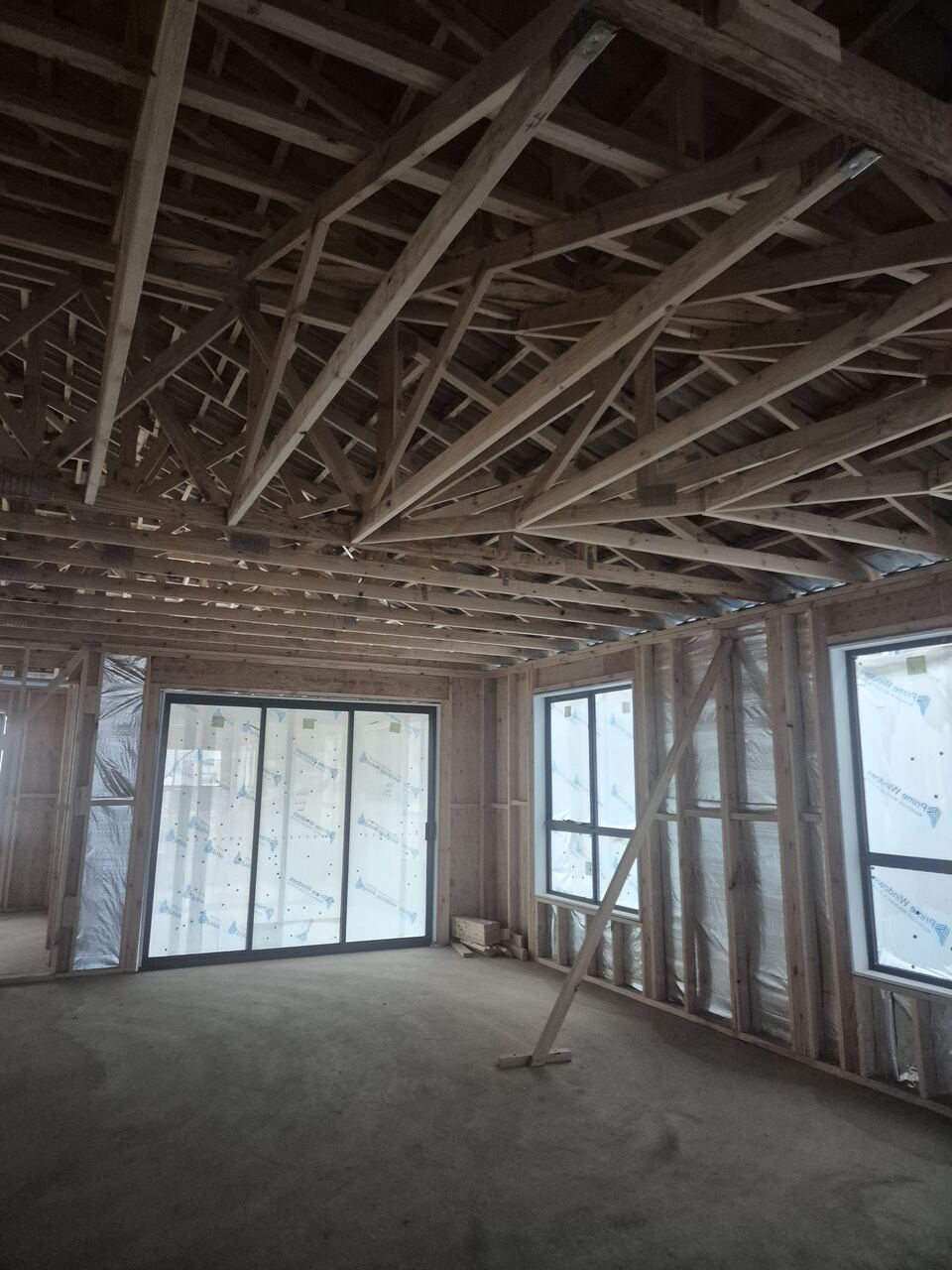 Main living area at Ladhams Way at frame stage, with windows installed and roof trusses exposed