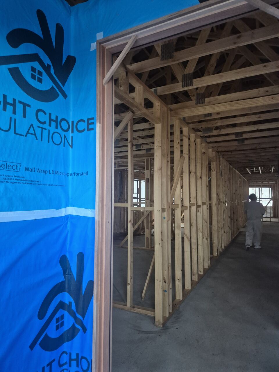 Inside the frame at Ladhams Way, with wall wrap on the external walls and a hallway of timber studs