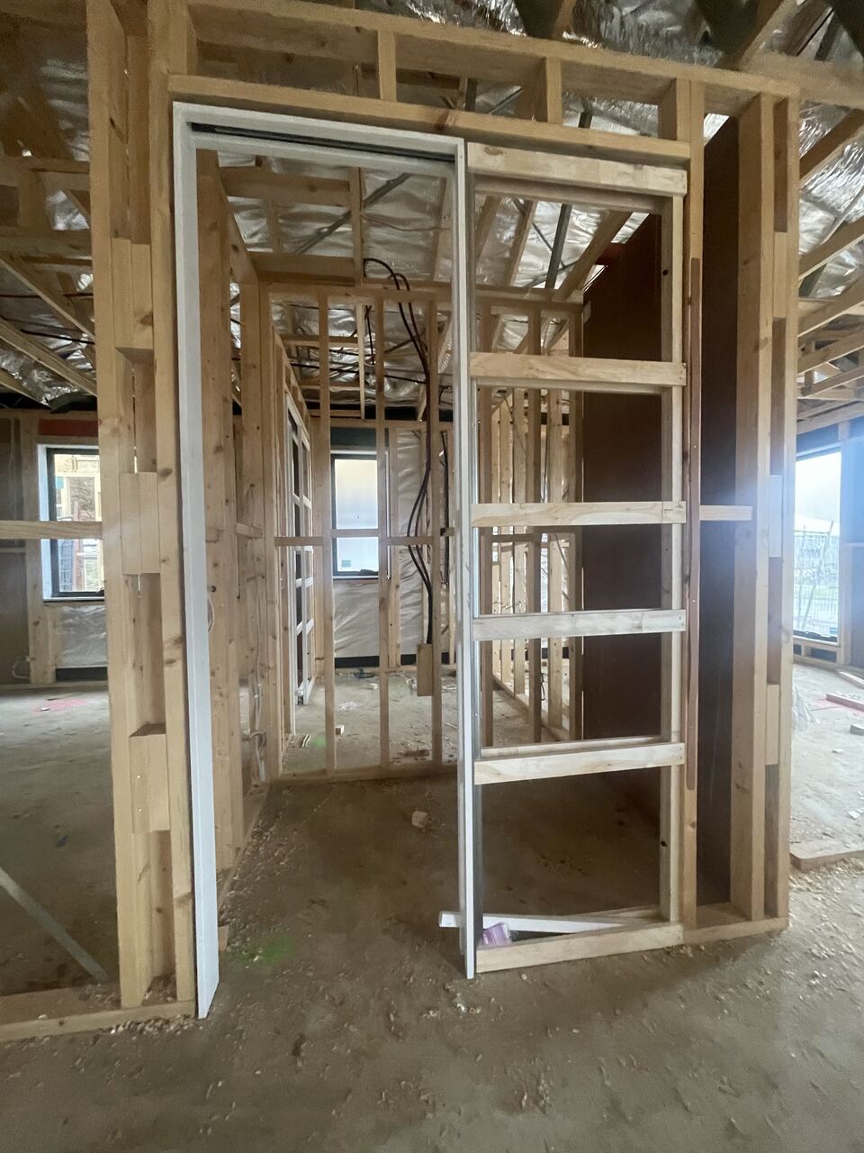 Inside the frame at Lucania Crescent with door frames installed and electrical wiring run through the studs