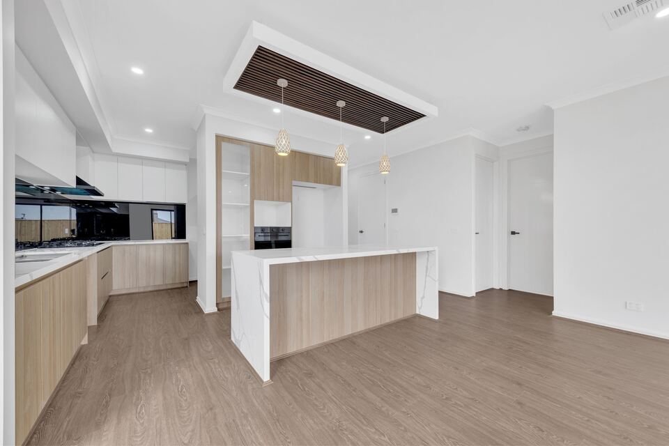 Kitchen at Lucania Crescent with timber-look cabinetry, a stone-topped island bench and a slatted timber ceiling feature