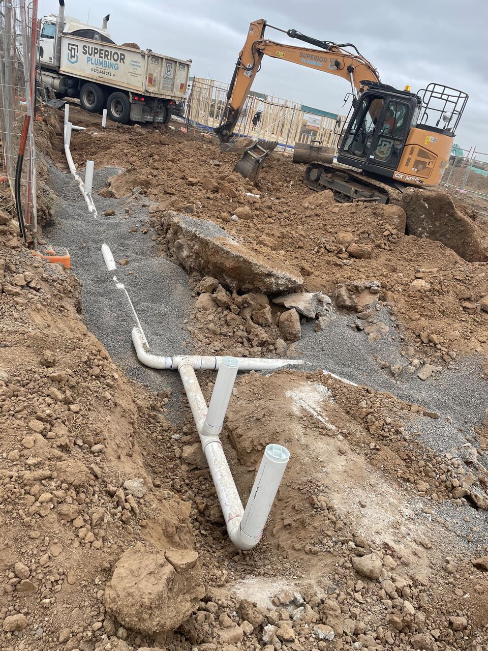 Excavator and truck on the Lucania Crescent block with drainage pipes laid in a trench before the slab